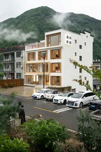 Modern residential building with a white exterior featuring large windows and a modern architectural design.