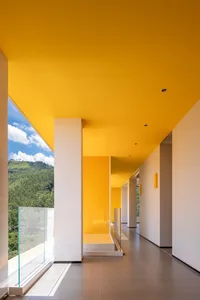 A modern interior with large windows, concrete walls, and yellow-painted ceiling and floor.
