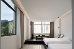 Modern minimalist bedroom featuring a clean, white design with floor-to-ceiling curtains and wooden flooring.