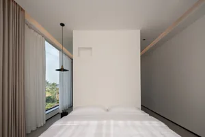 A minimalist bedroom with a white bedspread and a window.