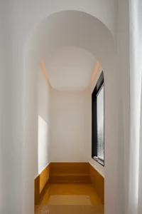 A minimalist bathroom with white tiled walls and floor, featuring a walk-in shower.