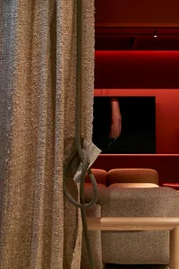 A textured fabric curtain with a rope tieback in a cozy residential living room setting.
