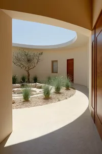 Concrete patio area with a tree, seating, and plants.