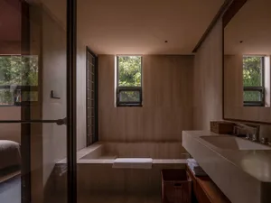 Modern luxury bathroom featuring a concrete bathtub and wooden accents.