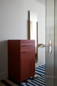 A minimalist bedroom features a metal dresser with drawers and a cabinet.