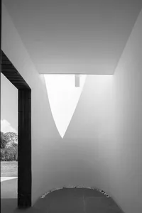 Interior of a minimalist space with concrete walls, a skylight, and a view of an outdoor space.