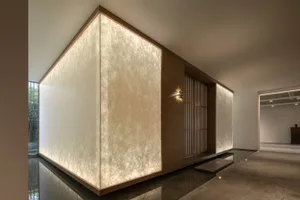 A minimalist lobby with paper walls and wooden partitions illuminated by warm lighting.