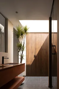 Modern minimalist bathroom with wooden cabinets and cement floor.