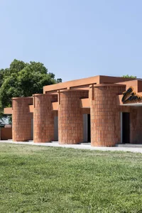 Modern brick architectural decoration with cylindrical pillars and flat roof in an outdoor setting with green grass.