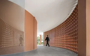 A modern architectural corridor featuring brick walls with a curved design and open layout.