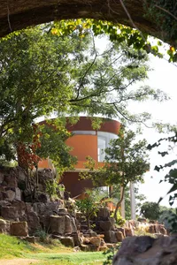 A modern house with clay exterior materials surrounded by trees and rocks.