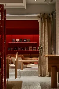 A modern coffee shop featuring red walls, white wooden tables, and a cement floor.