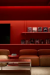 Modern living room with concrete walls and floor, leather sofa, and fabric seating