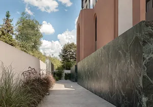 Modern exterior featuring textured marble walls and green foliage