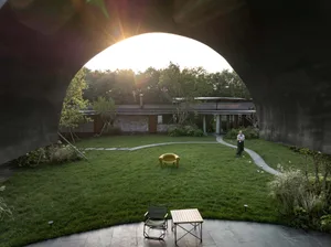 Modern garden with concrete paths, glass walls, and green grass.