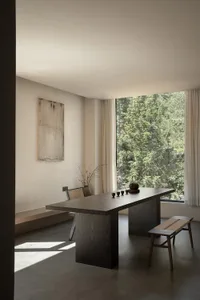 A modern industrial interior design featuring minimalist furniture, a rustic wooden table, and floor-to-ceiling windows with 