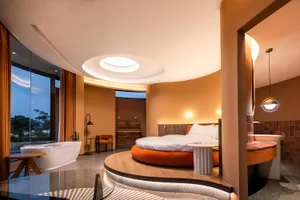 Modern minimalist bedroom with circular bed, large window, and circular ceiling light.