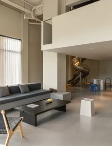 Modern office space with minimalist design, featuring concrete walls, wood furniture, and metal accents.