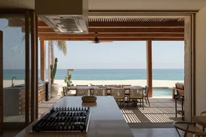 Modern open-concept kitchen overlooking the ocean with large windows, concrete floors, and a central island.