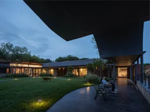 A modern residential courtyard featuring concrete, glass, and wooden elements