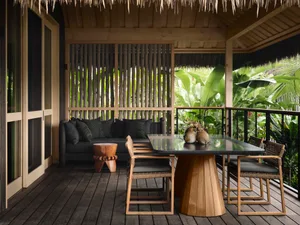 A modern residential deck with a tropical wood theme, featuring a cozy seating area with a comfortable sofa and wooden side t
