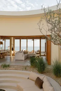 A modern residential interior featuring a cozy living area with a couch, coffee table, and large windows overlooking the ocea