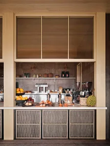 A well-equipped coffee shop counter with wooden paneling, featuring various baked goods and fruits.