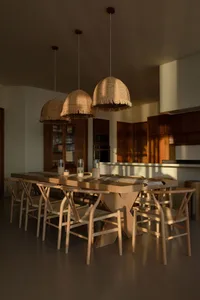 A minimalist dining room featuring rustic wooden furniture and woven rattan pendant lights.