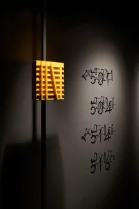 Minimalist metallic sculpture installation on a textured wall