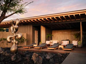 A modern residential lounge area with wooden furniture and a metal sculpture in the foreground.