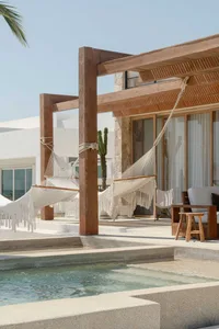 Wooden pergola with white hammocks over a concrete patio