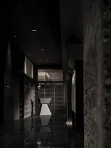 A dark, industrial-style corridor with concrete walls and a geometrically shaped table in the center.