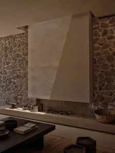 A modern interior space featuring a concrete fireplace with a stone wall backdrop.