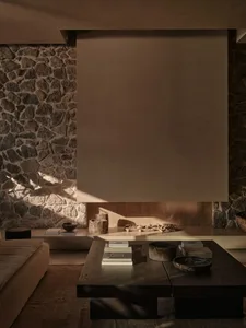 A modern living room with warm, earthy tones featuring a low wooden coffee table and a cozy stone fireplace.