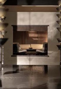 Modern living room with a concrete fireplace and seating area, featuring minimalist furniture and subdued lighting.