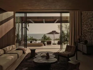 Modern living room featuring a sleek sofa, wooden coffee table, and a view of the sea.