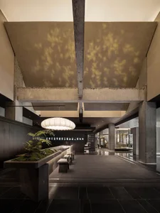 A modern lobby with concrete walls and a high ceiling with exposed beams.