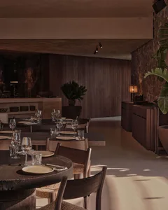 現代餐廳室內，圓形木桌搭配木椅，融合自然與工業材質。