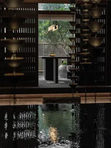 A modern spa setting with metal wall decor, featuring a minimalist design with a dark palette and a water feature.