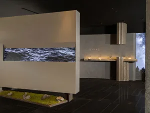 Modern spa reception with concrete and glass elements, featuring a water feature and starry night view.