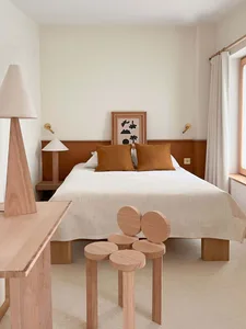 A minimalist bedroom with wooden furniture and a white bed.