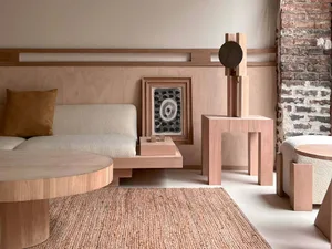 A minimalist living room featuring wooden furniture and a brick wall.