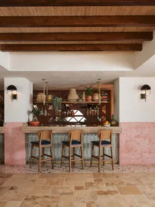 Modern bar interior with terrazzo flooring and wooden stools.