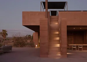 A modern building exterior with concrete walls and stairs, lit by warm lighting.