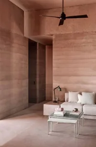 A modern living room with textured concrete walls, a minimalist sofa, and a low coffee table.