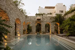 A modern hacienda with a stone pool and garden, featuring white walls and a warm, inviting outdoor space.