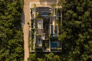 俯瞰一座以混凝土建造的現代住宅，周圍環繞茂密綠樹。