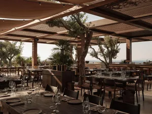 Modern restaurant interior with industrial design features, including wooden tables and glass elements.