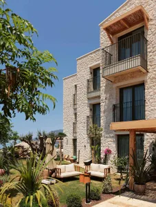 A modern residential house with stone exterior and garden area with patio furniture and greenery.