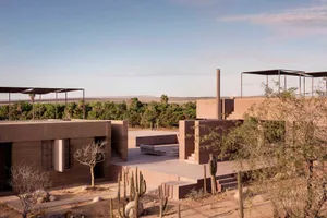 Modern vacation home with sandstone exterior in a desert landscape.